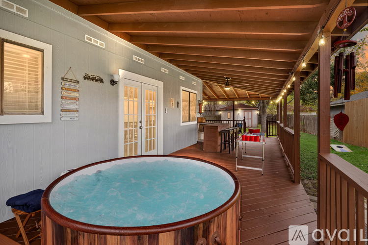 A hot tub is in the middle of a deck with a wooden floor.
