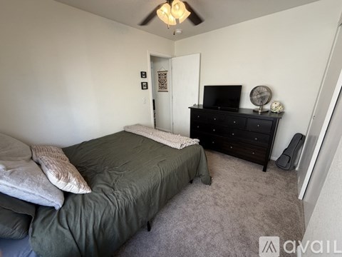 A bedroom with a bed, dresser, and ceiling fan.