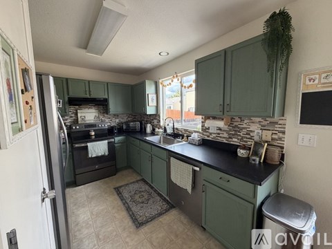 A kitchen with green cabinets and a black countertop.