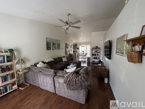A living room with a grey couch and a fan on the ceiling.