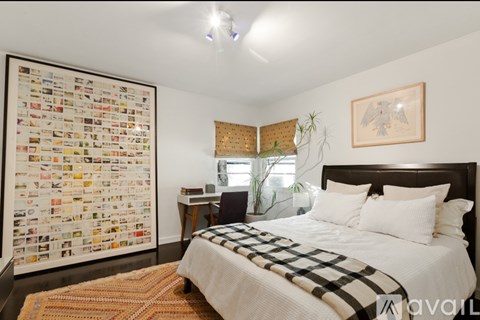 A bedroom with a large poster on the wall and a bed with a checkered blanket.