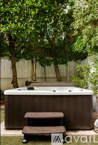 A hot tub sits in a backyard surrounded by trees.