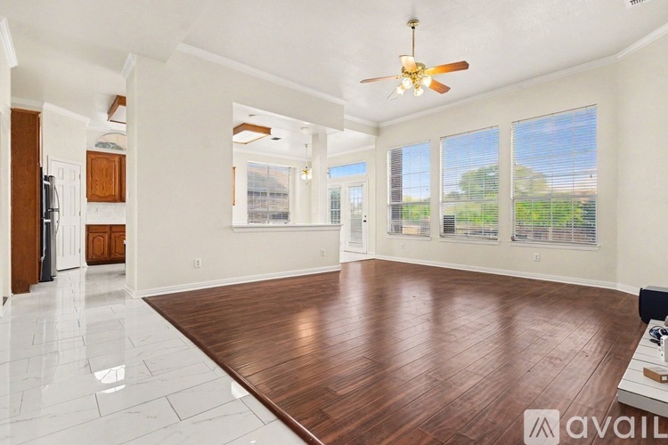 A spacious room with a wooden floor and a ceiling fan.