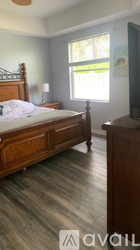 A bedroom with a bed, dresser, and window.