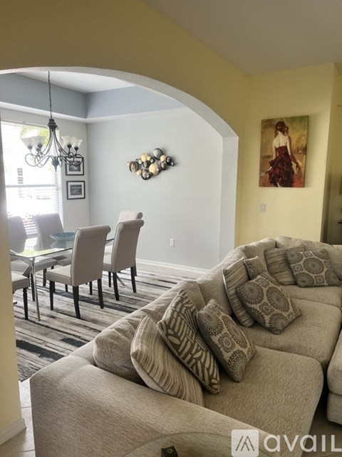 A living room with a couch, chairs, and a painting on the wall.