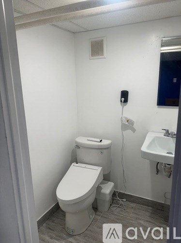 A white toilet with a white sink and a black phone on the wall.