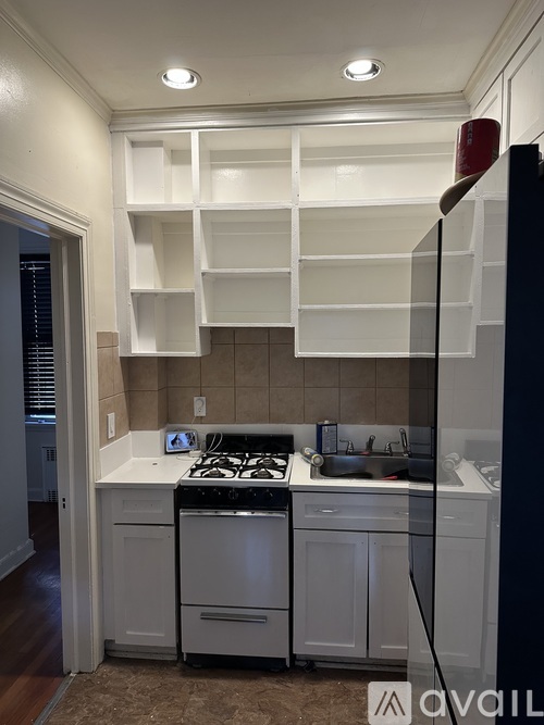 A kitchen with white cabinets and a black refrigerator.