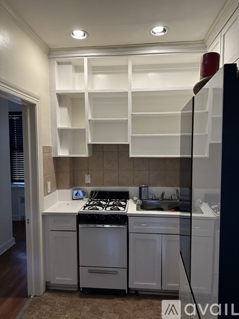 A kitchen with white cabinets and a black refrigerator.