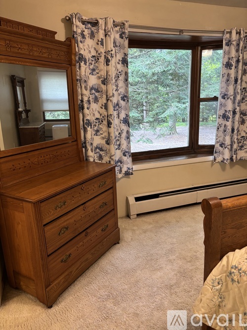 A bedroom with a wooden dresser and a mirror.