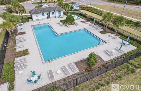 A large outdoor swimming pool surrounded by a black fence and several lounge chairs.
