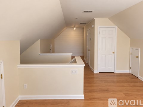 A spacious room with wooden floors and white walls.