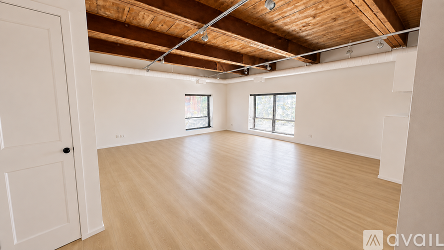 A spacious room with wooden floors and a white door.