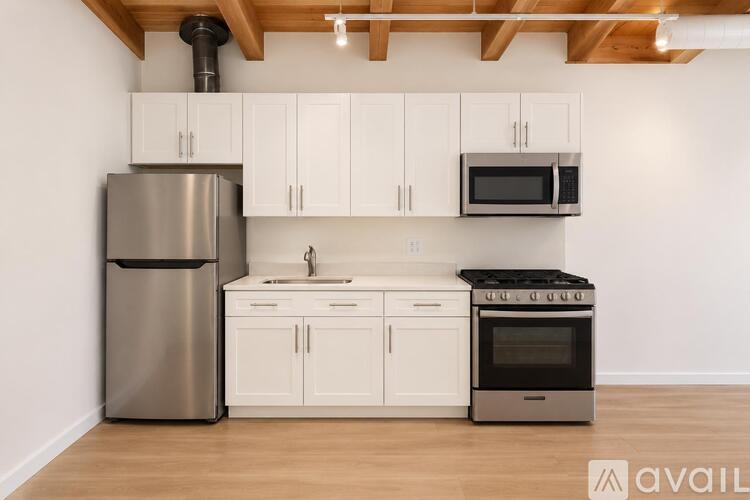 A kitchen with white cabinets and a stainless steel refrigerator.