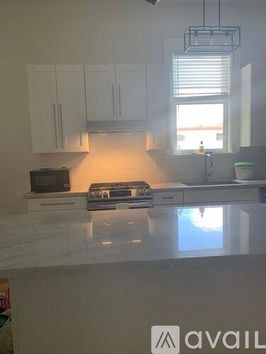 A kitchen with white cabinets and a countertop with a microwave and toaster on it.