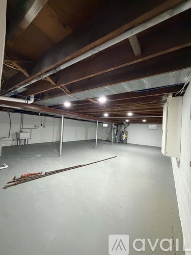 A spacious room with wooden beams on the ceiling and a pair of skis leaning against the wall.