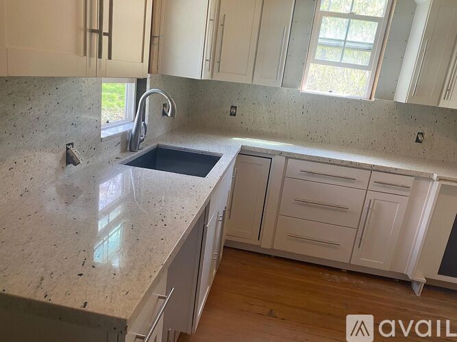 A kitchen with granite countertops and white cabinets is available for rent.