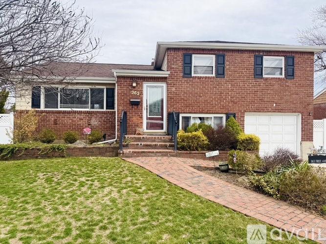 A red brick house with a white garage door and a brick pathway leading to the front door.