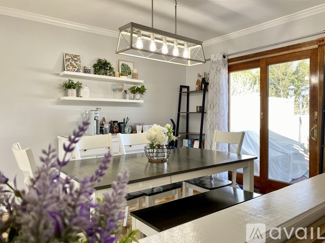A modern kitchen with a dining table and chairs, a black countertop, and a white interior.