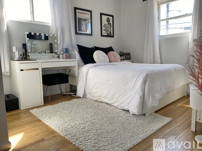 A bedroom with a white bed and a vanity table with a mirror.
