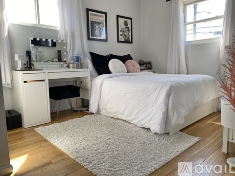 A bedroom with a white bed and a vanity table with a mirror.