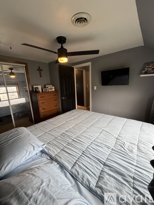 A bedroom with a large bed and a ceiling fan.