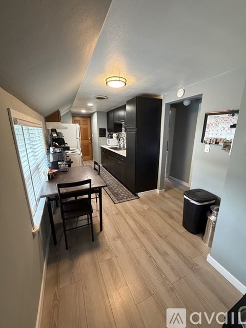 A kitchen with a table and chairs in the foreground and a fridge and cupboard in the background.