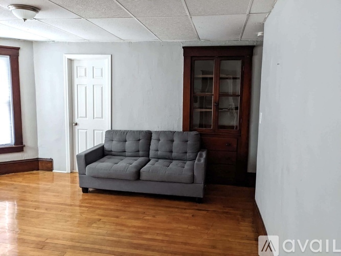 A grey couch is in a room with wooden floors and white walls.