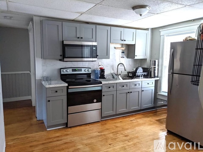 A kitchen with wooden floors and a refrigerator on the right.