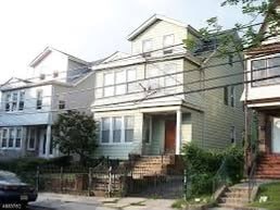 A house with a green door is in front of a house with a white door.