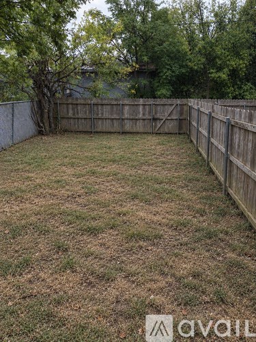 A backyard with a wooden fence and a tree.