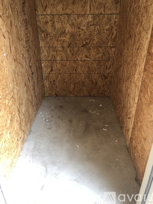 A room with a concrete floor and walls covered in plywood.