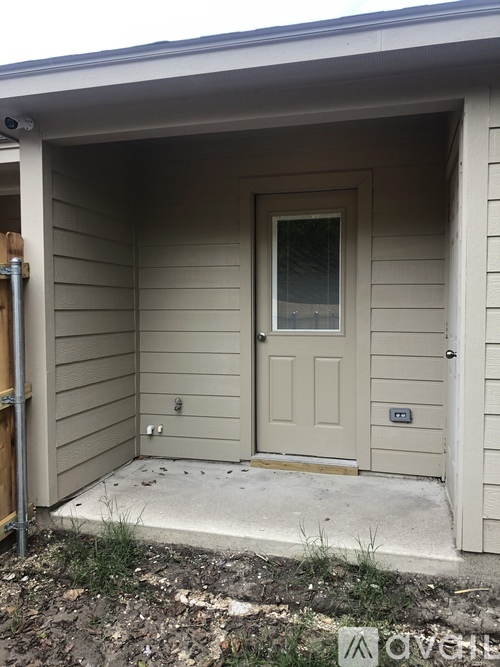 A small beige house with a white door and a small window.