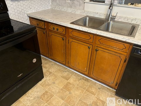 A kitchen with wooden cabinets and a black dishwasher.