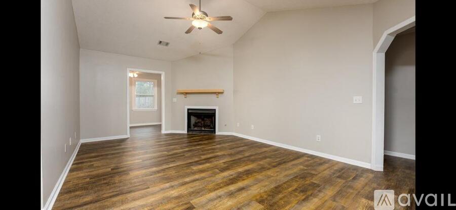 A spacious living room with wood flooring and a fireplace.