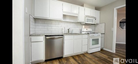 A kitchen with white cabinets and a wooden floor.
