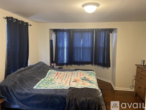 A bedroom with a bed, a dresser, and a window with curtains.