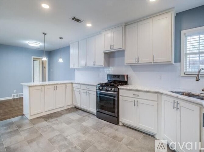 A kitchen with white cabinets and a black stove top oven.