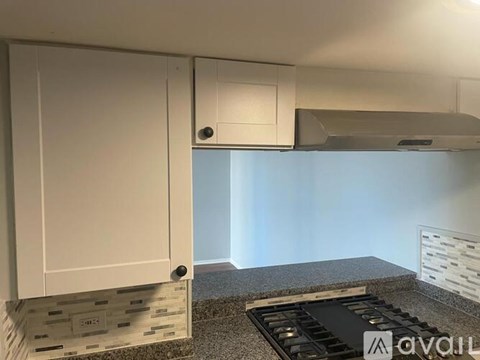 A kitchen with white cabinets and a black stove top.