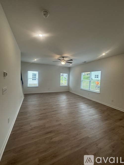 A spacious room with wooden flooring and a ceiling fan.