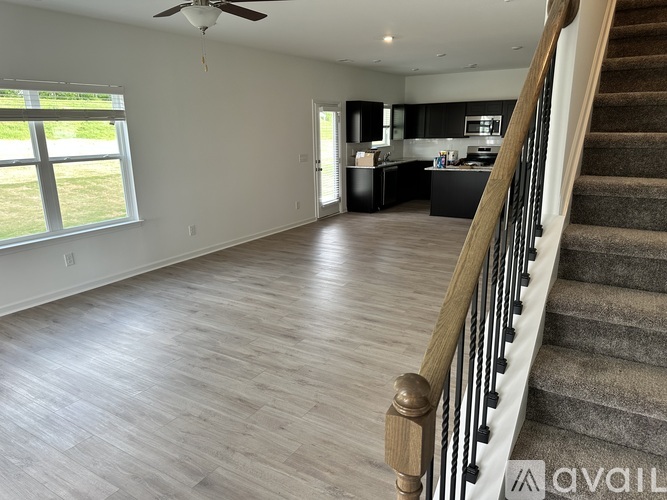 A spacious living room with a staircase leading to the kitchen.