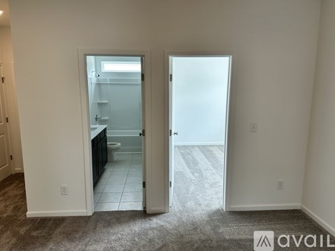 A room with two open doors leading to a kitchen and bathroom.