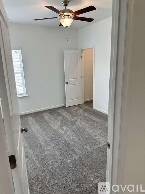 A room with a ceiling fan and carpeted floor.