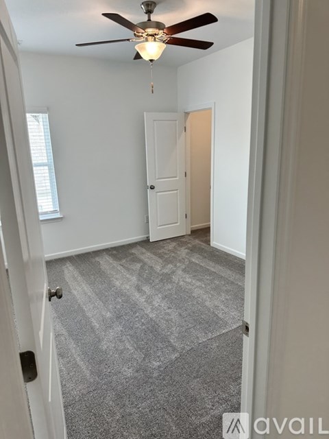 A room with a ceiling fan and carpeted floor.