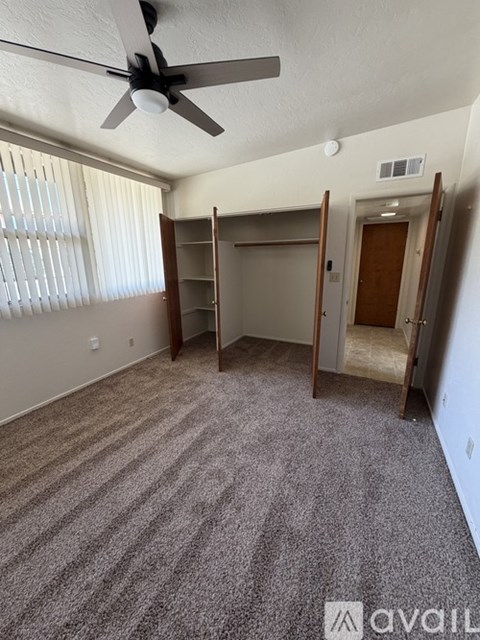 A room with a ceiling fan and carpeted floor.