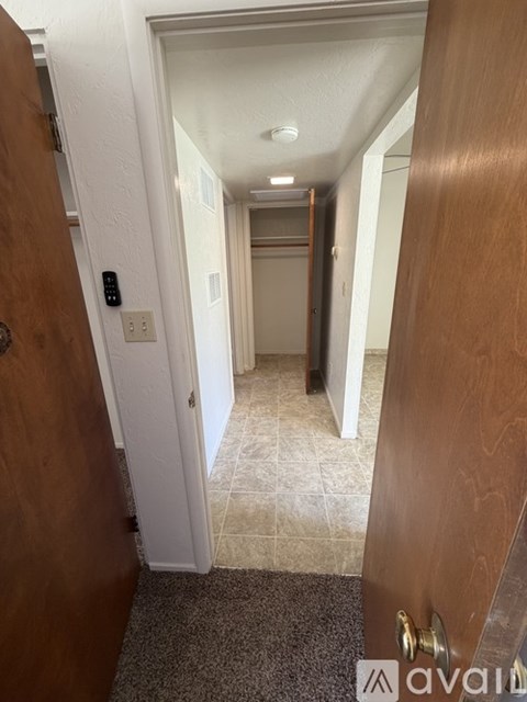 A hallway with a door on the right and a light switch on the wall.