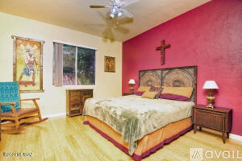 A bedroom with a bed, a chair, and a painting on the wall.