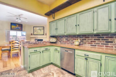 A kitchen with green cabinets and a brick backsplash.