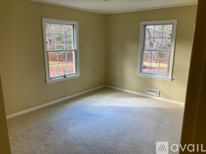 A room with two windows and carpeted floor.