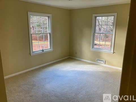 A room with two windows and carpeted floor.