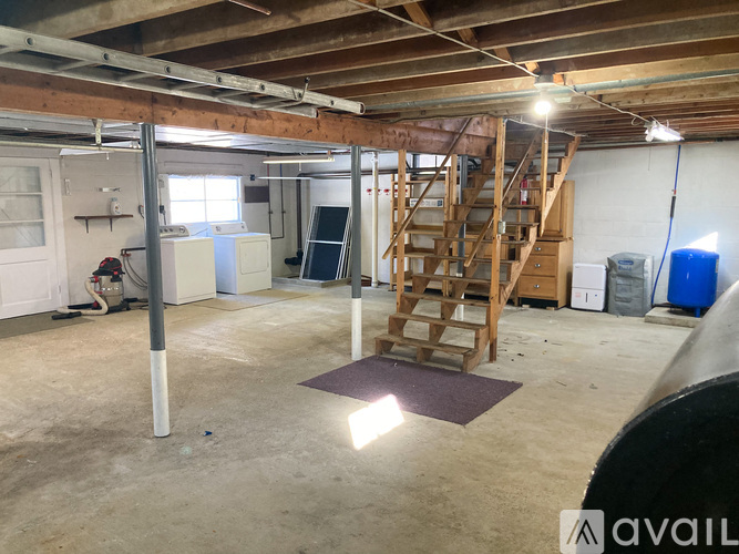 A large empty room with a ladder and a purple mat on the floor.